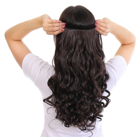 Person wearing a long, wavy hairpiece with a plain background